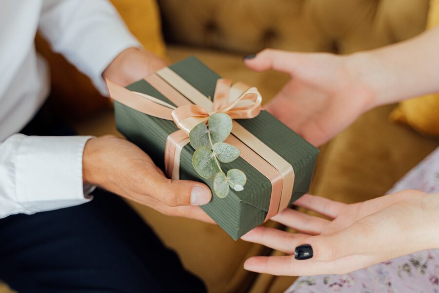 Two people exchanging a ribbon-tied gift box